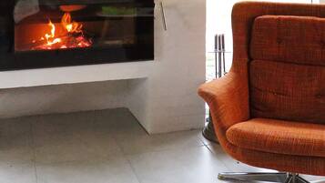 A modern living room with a fireplace, a comfortable orange armchair, and a tiled floor.