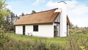 A modern house with a thatched roof, a large glass door, and a white exterior.