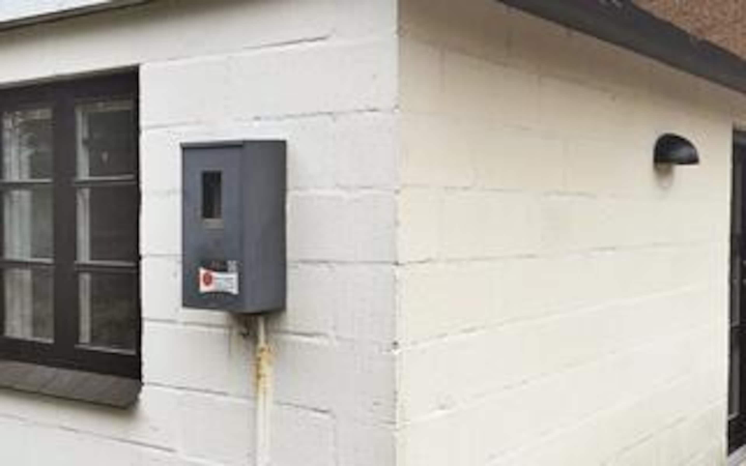 A building exterior with a window, a door, and a wall-mounted electrical box.