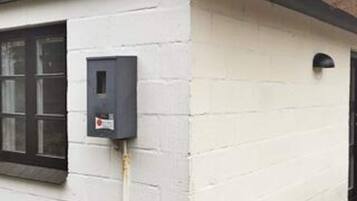 A building exterior with a window, a door, and a wall-mounted electrical box.