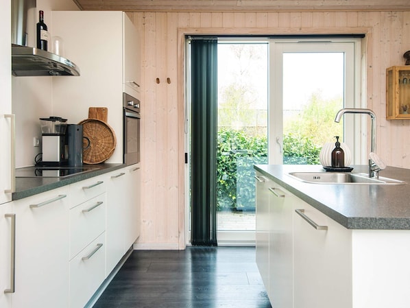 A modern kitchen with a built-in oven, a coffee machine, and a large window. - 4 Star Holiday Home in Glesborg (Glesborg)