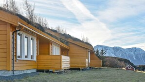 A row of wooden cabins with a mountain backdrop. - 4 Star Holiday Home in Aukra (Aukra)