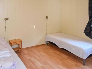 A room with a bed, a small wooden nightstand, and a single light fixture on the wall. - 4 Star Holiday Home in Aukra (Aukra)