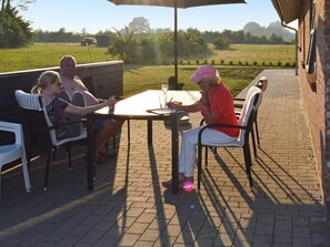 A patio with a brick floor, outdoor furniture, and a table with a drink.