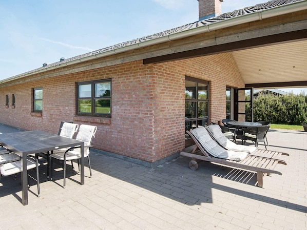 A patio area with a brick wall, a table, and lounge chairs.