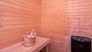 A sauna room with wooden walls, a bench, and a black trash bin. - 8 Person Holiday Home in Sydals-by Traum (Sydals)