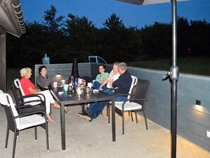 A group of people seated around a table with chairs, a table lamp, and a bottle on the table.
