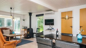 Un salon moderne doté d’une cheminée, d’un coin repas et d’un téléviseur fixé au mur.
