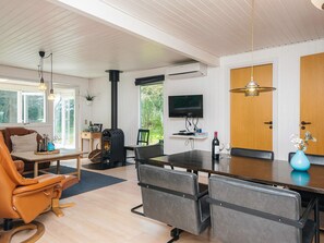 Moderni olohuone, jossa on takka, ruokailutila ja seinälle asennettu televisio.