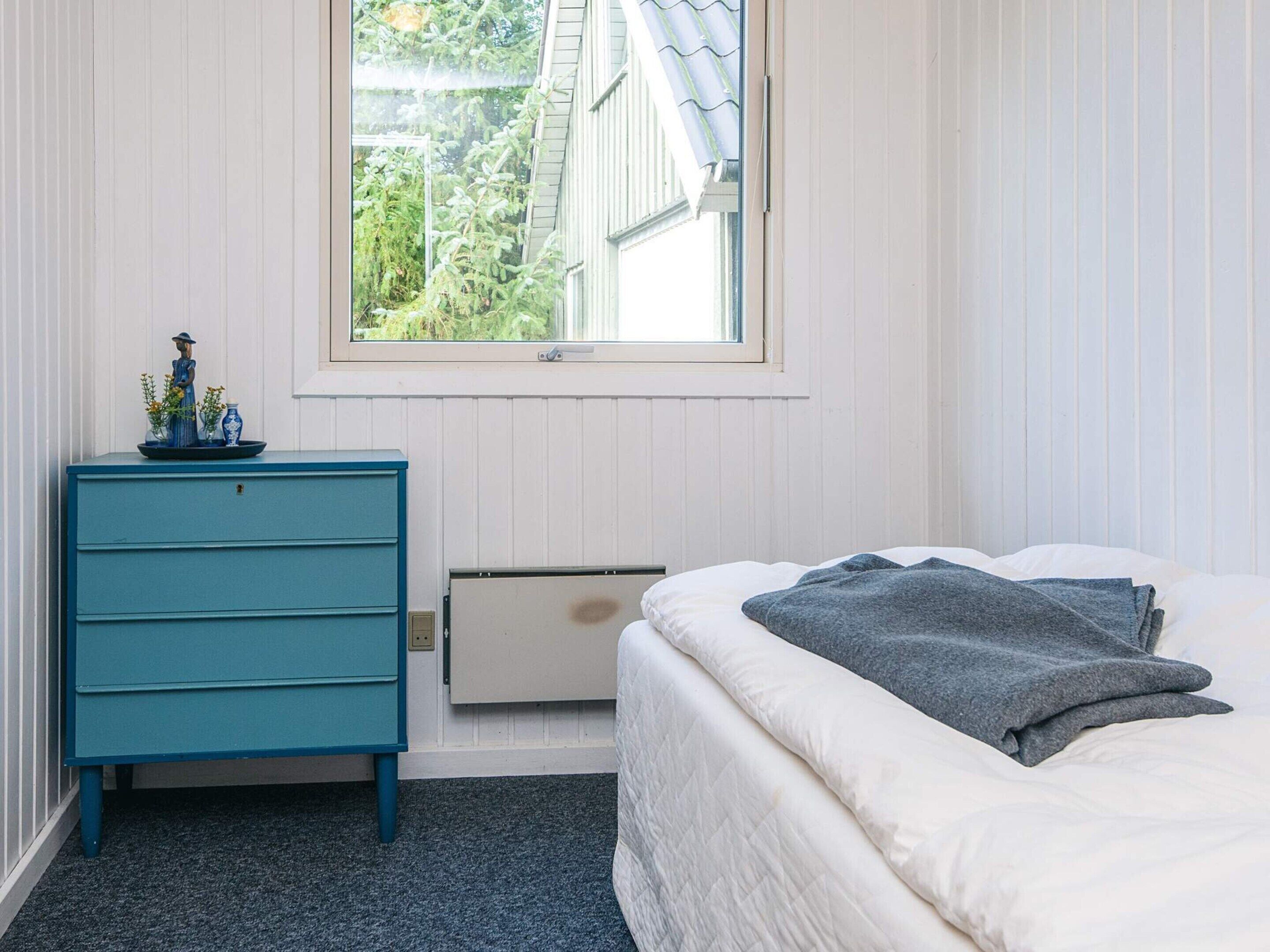 Un dormitorio con cama, cómoda y ventana.