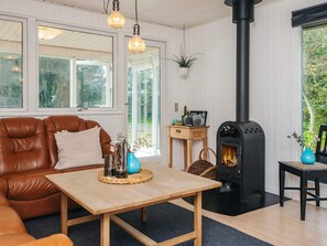 Tunnelmallinen olohuone, jossa on nahkasohva, puinen pöytä ja musta puukamiina.
