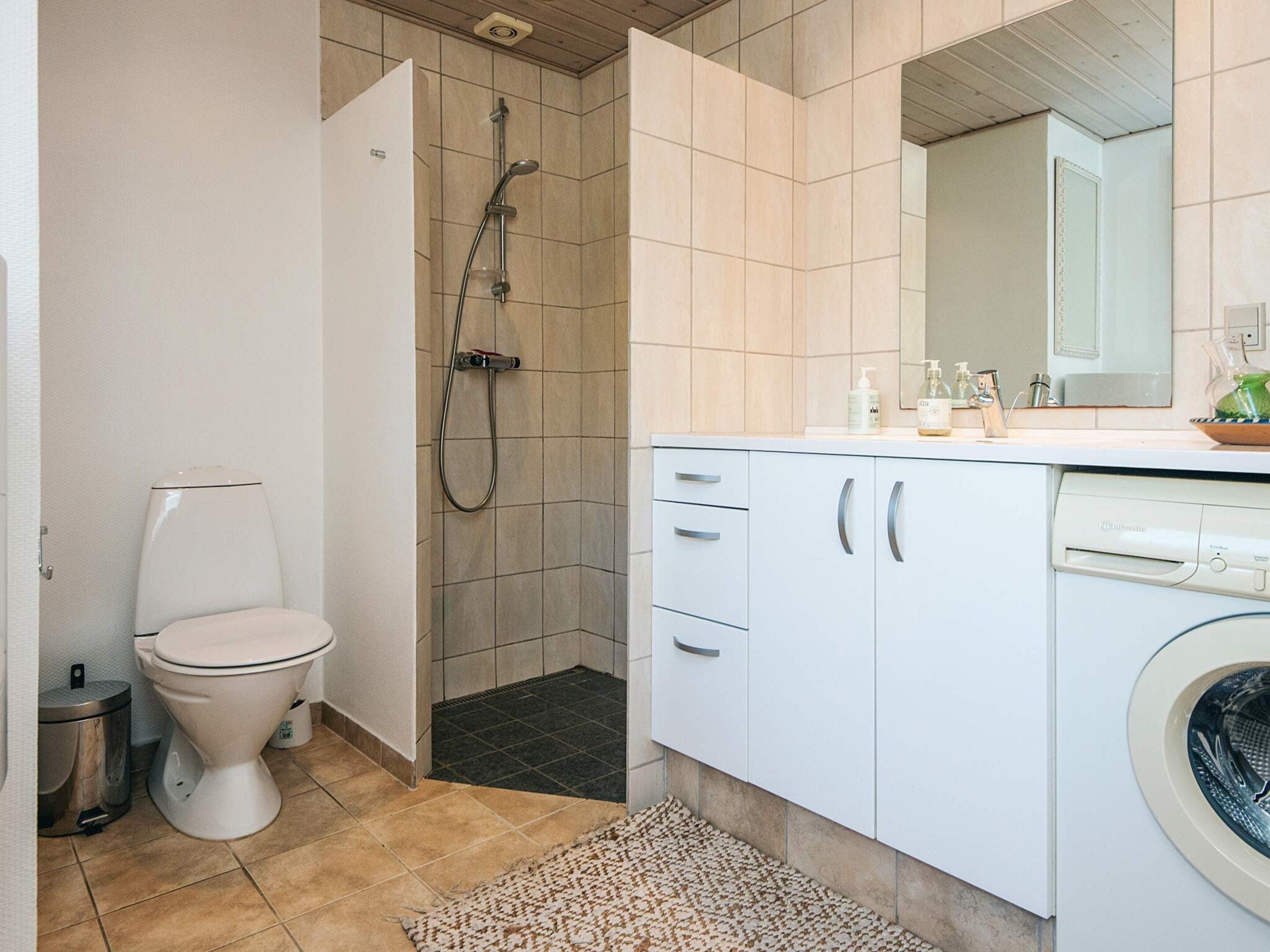 Kylpyhuone, jossa on wc, suihku ja pesukone.