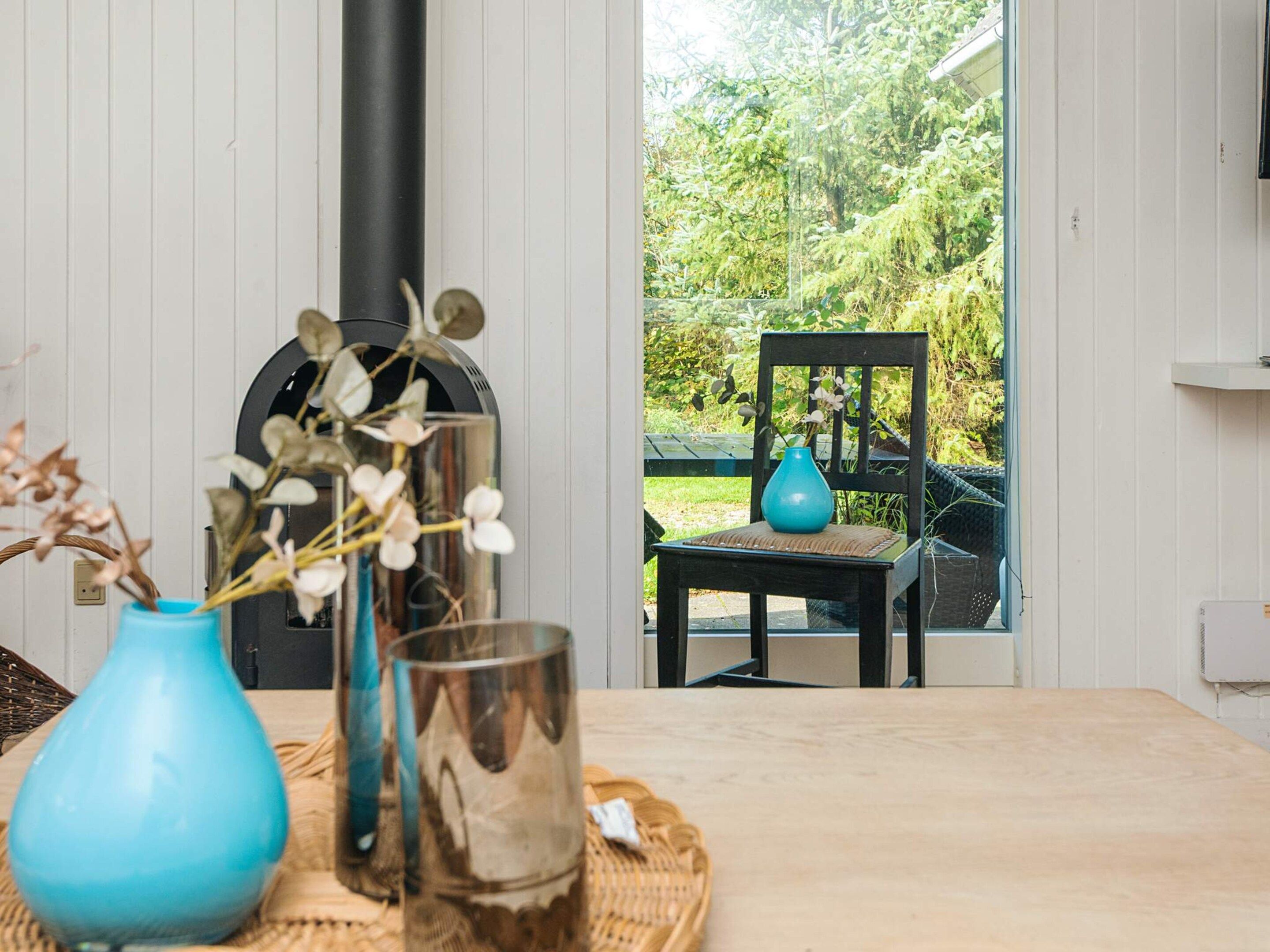 A room with a table, chairs, and a view of greenery outside.