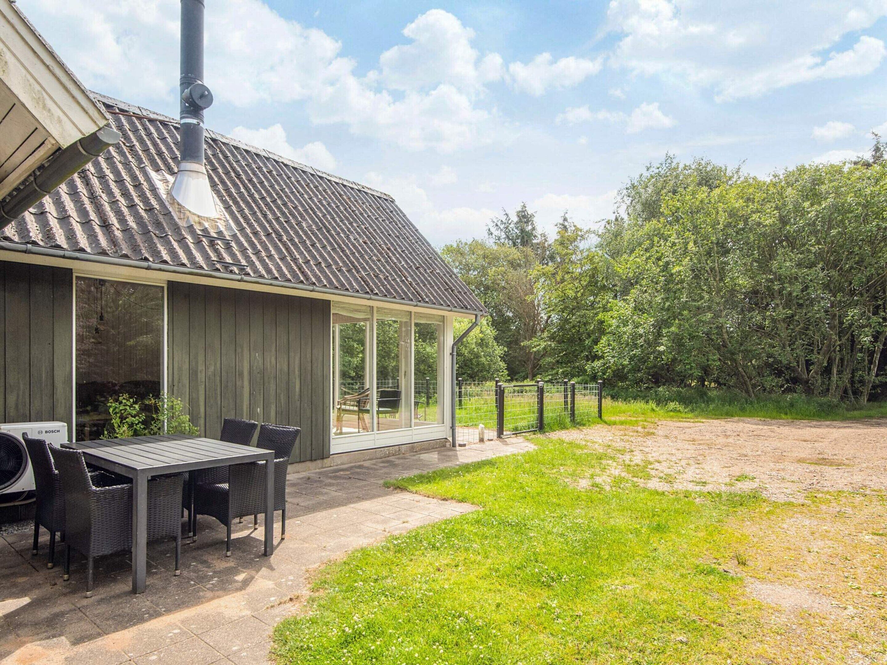 A modern house with a covered patio, a dining table, and chairs.