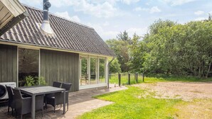 Une maison moderne dotée d’un patio couvert, d’une table à manger et de chaises.
