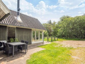 Moderni talo, jossa on katettu terassi, ruokapöytä ja tuolit.