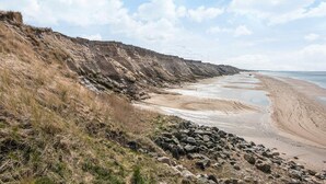 A coastal landscape with a sandy beach, rocky cliffs, and a clear sky. - 6 Person Holiday Home in Lokken (Lokken)