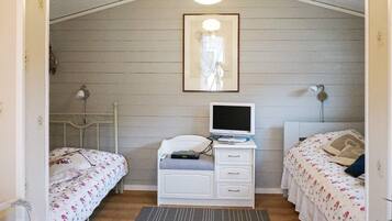A room with two beds, a desk with a computer, a lamp, and a framed picture on the wall.