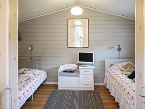 A room with two beds, a desk with a computer, a lamp, and a framed picture on the wall.