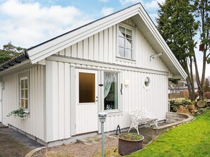 A white building with a gabled roof, a front door, and a bench outside.