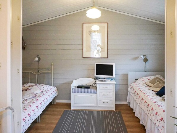 A small, cozy room with two single beds, a white dresser with a television, and a framed picture on the wall. - Holiday Home in Fängersfors (Falkenberg)