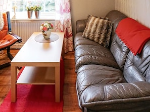 A living room with a leather sofa, a wooden table, and a red rug. - Holiday Home in Fängersfors (Falkenberg)