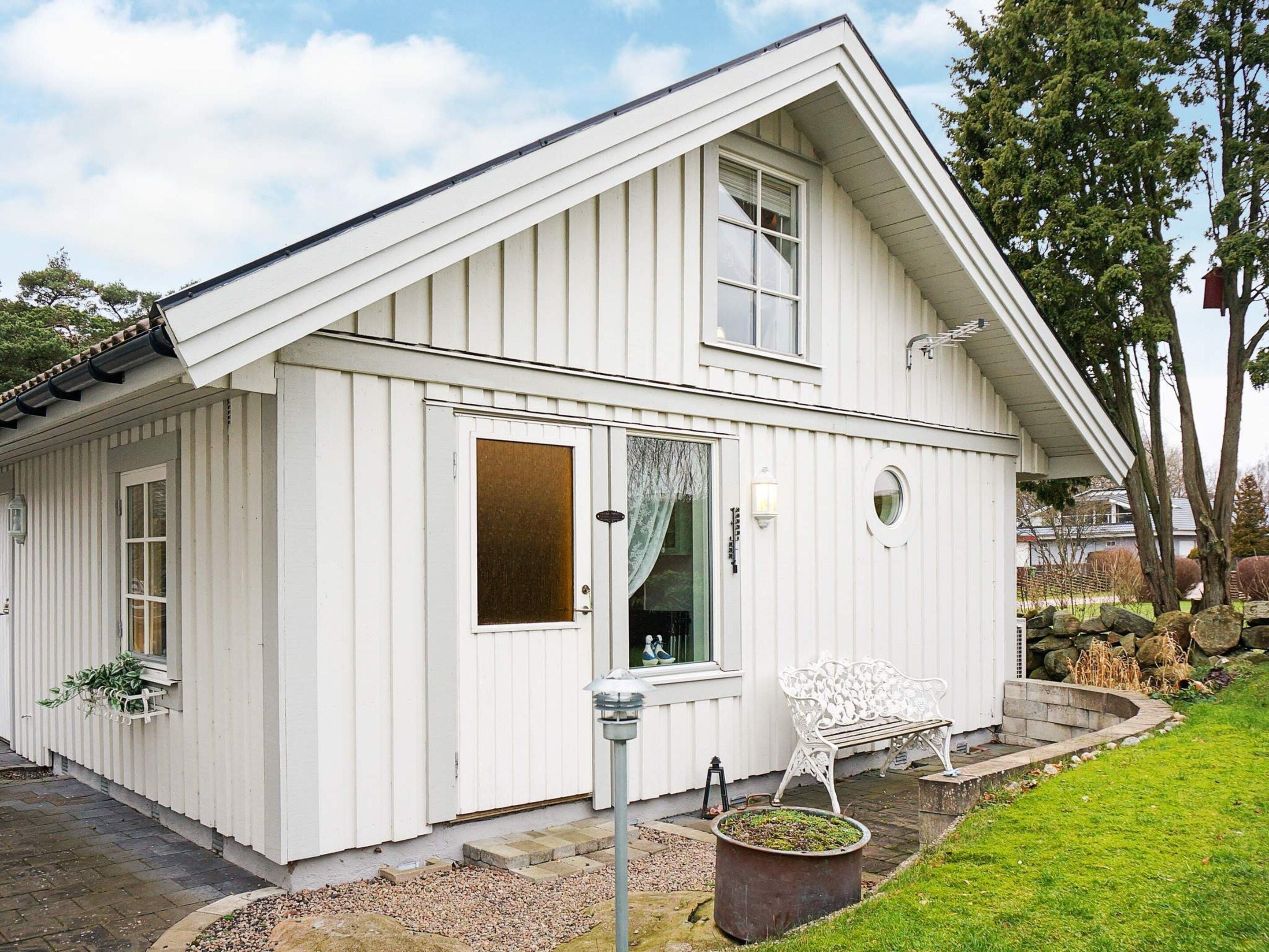 A white building with a gabled roof, a front door, and a bench outside.