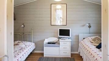 A room with two single beds, a white dresser with a television, and a framed picture on the wall.