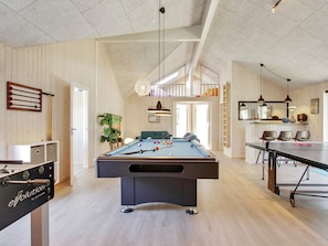 A spacious room with a pool table, a foosball table, and a ping pong table. There is a seating area with chairs and a sofa. - 5 Star Holiday Home in Frederiksvaerk (Frederiksvaerk)