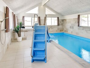 A swimming pool with a blue slide, a potted plant, and a shower area. - 5 Star Holiday Home in Frederiksvaerk (Frederiksvaerk)