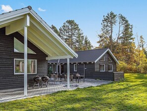 A two-story house with a covered patio area, a grill, and a lawn. - 5 Star Holiday Home in Frederiksvaerk (Frederiksvaerk)