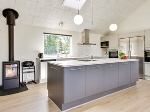 Una cocina moderna con una isla central, electrodomésticos de acero inoxidable y una estufa de leña.