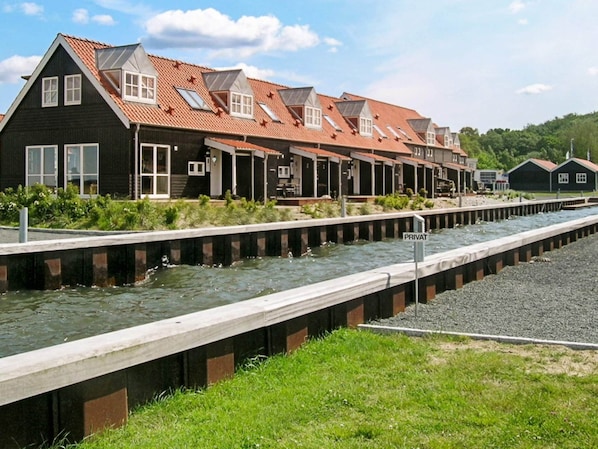 A row of houses with sloped roofs and skylights, a water channel, and a 'PRIVAT' sign.