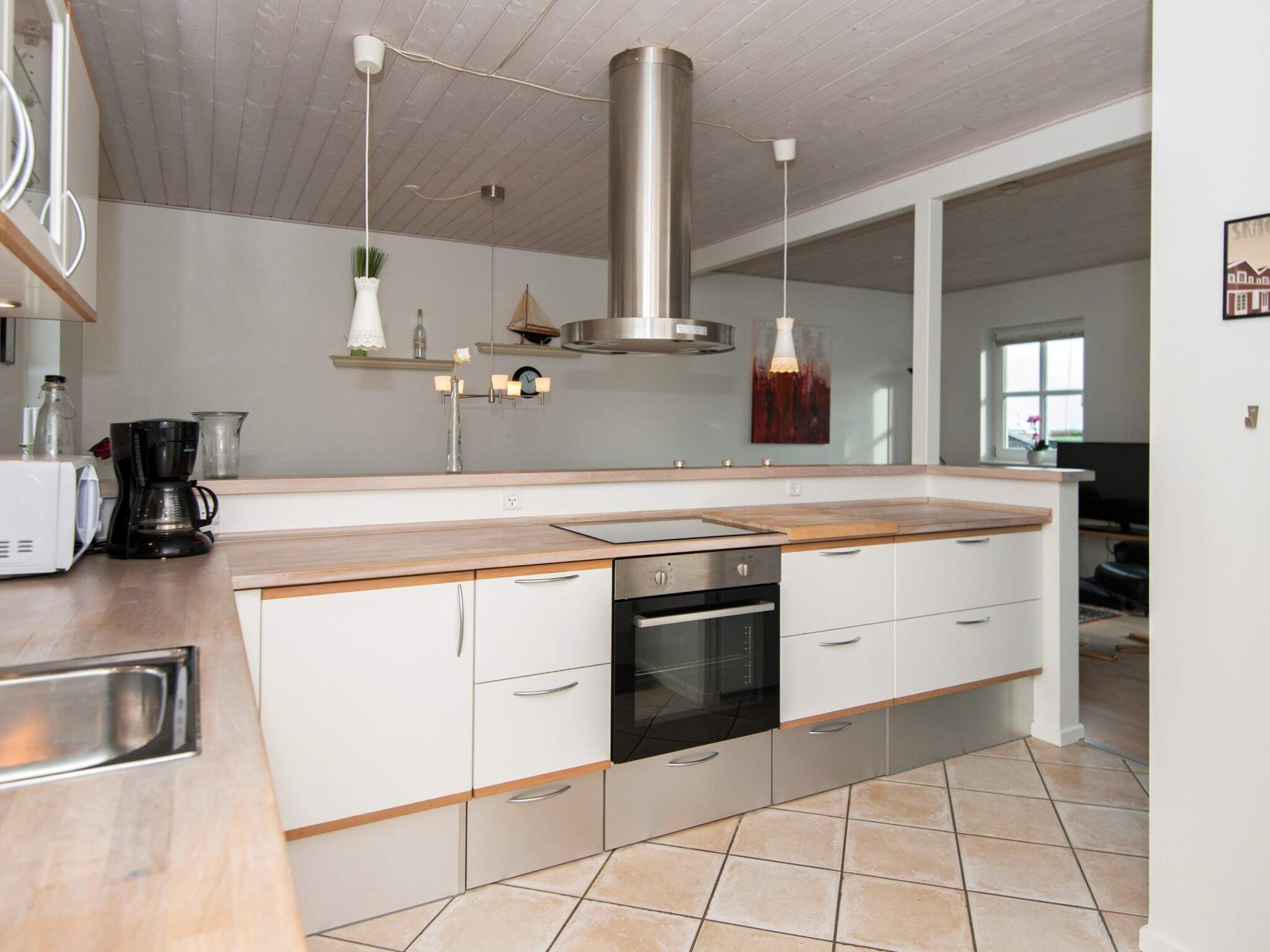 A modern kitchen with a central island, stainless steel appliances, and a hanging light fixture.