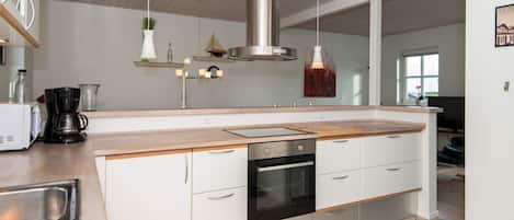 A modern kitchen with a central island, stainless steel appliances, and a hanging light fixture.