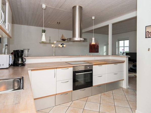 A modern kitchen with a central island, stainless steel appliances, and a hanging light fixture.