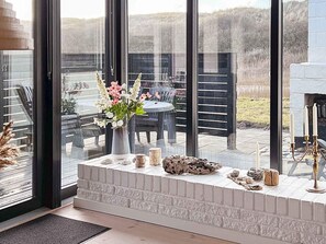 A modern interior with a fireplace, a vase of flowers, and a view of the outdoors. - 5 Person Holiday Home in Harboore (Harboore)