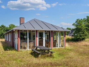 A small, single-story structure with a sloped roof, large glass windows, and a wooden bench in front.