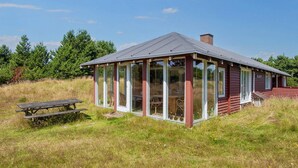 En liten, envåningsbyggnad med ett sluttande tak, stora glasfönster och en träveranda.