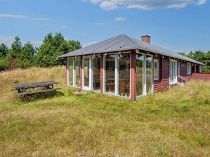 A small, single-story building with a sloped roof, large glass windows, and a wooden deck. - 5 Person Holiday Home in Fano (Fano)