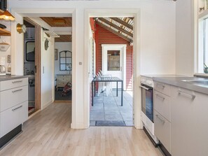 A kitchen with a dining area, wooden flooring, and a red exterior wall. - 5 Person Holiday Home in Fano (Fano)
