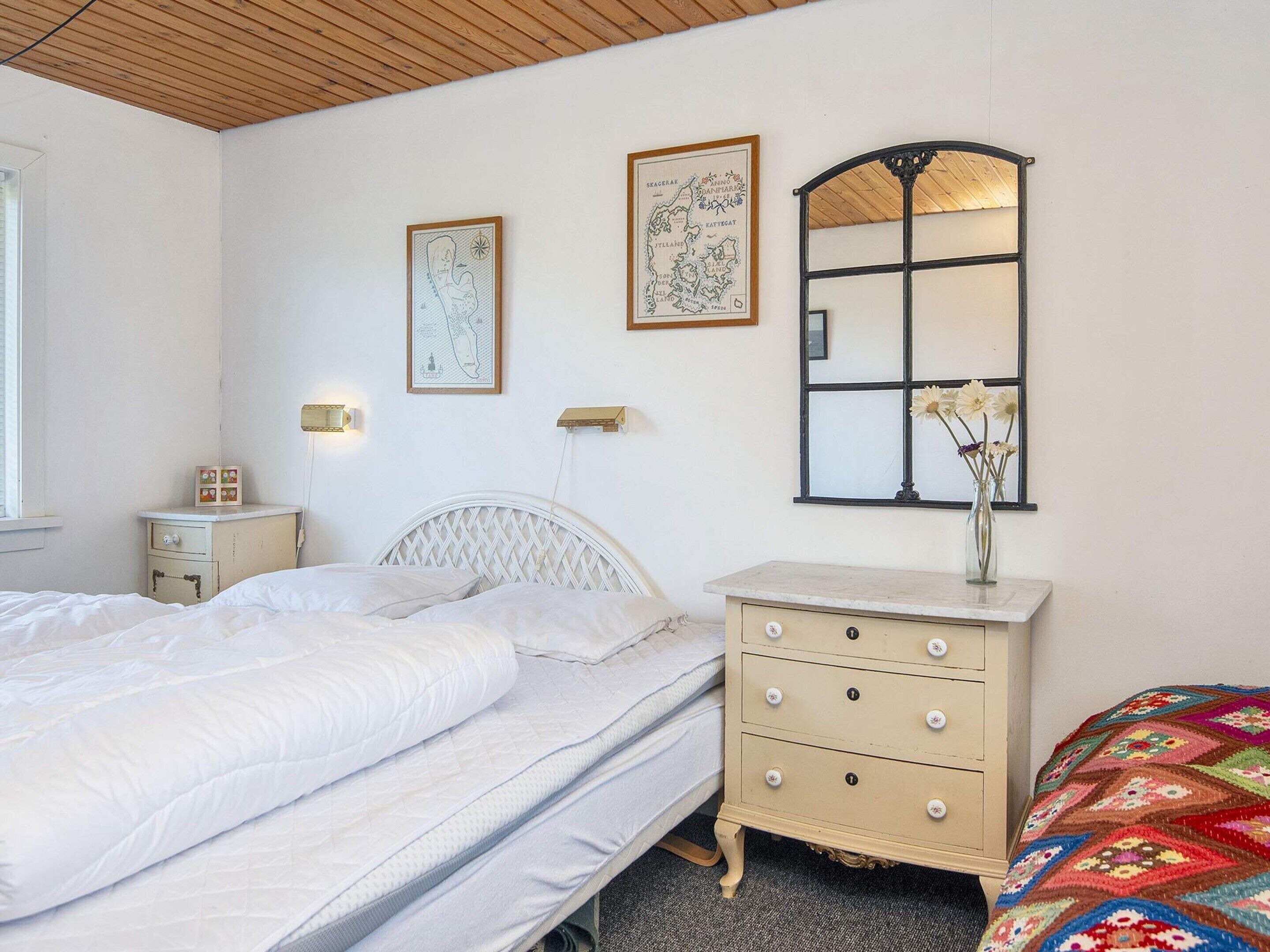 A bedroom with a bed, a dresser, a nightstand, and a mirror.