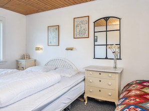 A bedroom with a bed, a dresser, a nightstand, and a mirror.