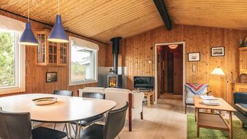 Interior acogedor de una cabaña con comedor, sala de estar y chimenea.
