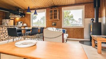 Interior acogedor de una cabaña con comedor, cocina y zona de estar.