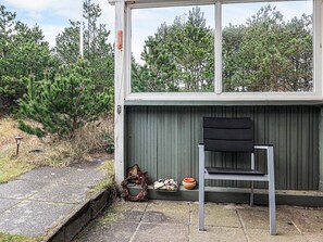 A small outdoor seating area with a metal chair and a bench, a wreath, and a tray with food items. - 6 Person Holiday Home in Thisted (Thisted)