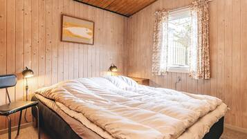 Un dormitorio con una cama, dos lámparas de noche, una ventana con cortinas y un techo de madera.