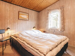A bedroom with a bed, two bedside lamps, a window with curtains, and a wooden ceiling. - 6 Person Holiday Home in Thisted (Thisted)