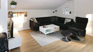 A modern living room with a black sectional sofa, a white coffee table, a black armchair, and a grey patterned rug. - Lovely Holiday Home with Terrace near Hadsund (Hadsund)