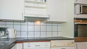 A compact kitchen with a built-in dishwasher, a microwave, and a washing machine. - 6 Person Holiday Home in Orsted-by Traum (Ørsted)